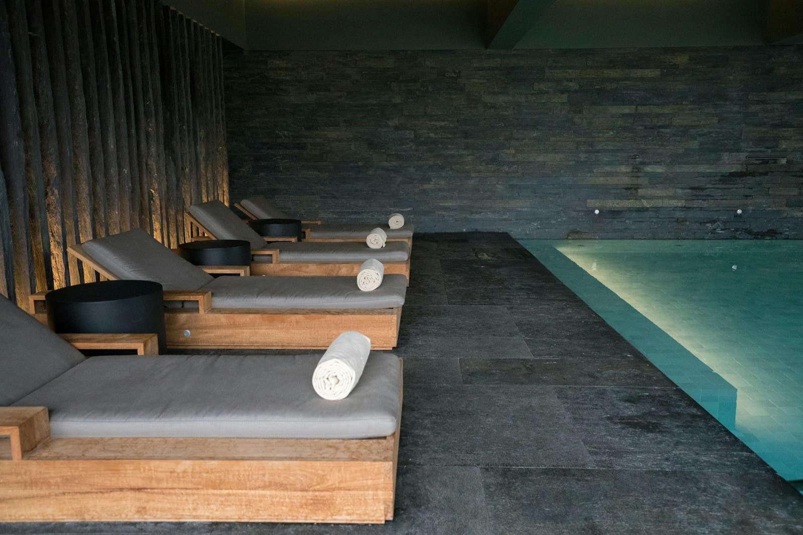 Camastros junto a alberca interior en un spa premium